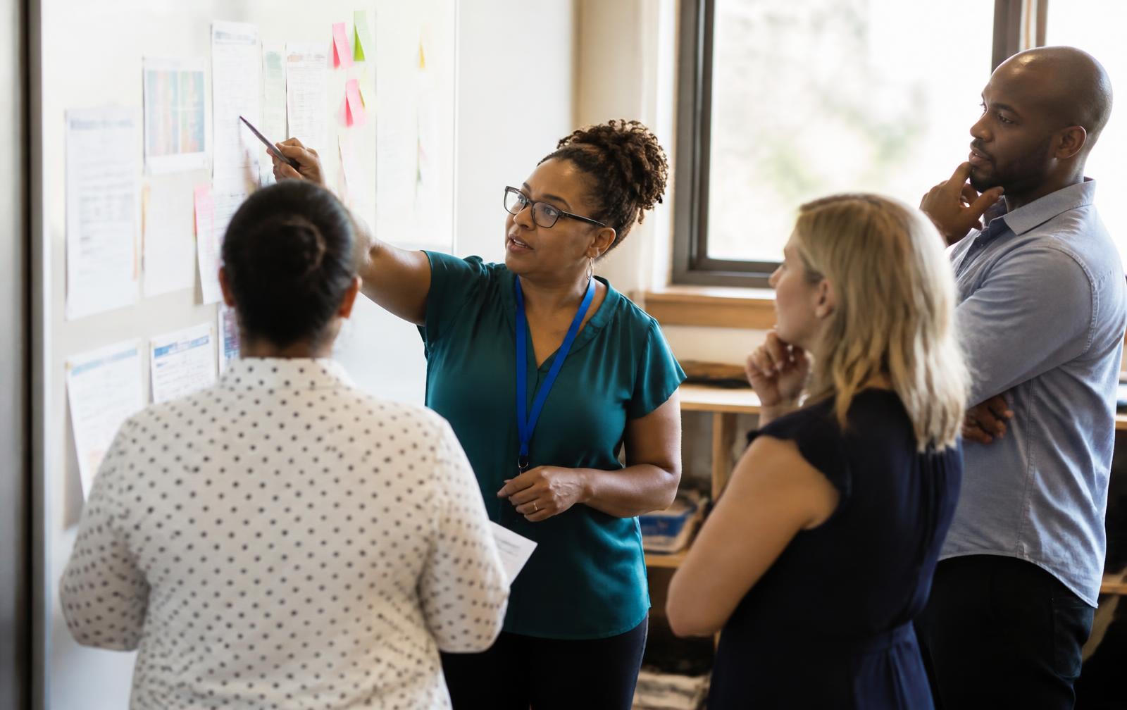 Educators in a planning meeting at a whiteboard with notes and documents